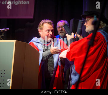 Brighton, UK. 27th July, 2015. Summer graduations at the University of Brighton. Luke Cresswell (left) and Steve McNicholas (right) the founders of Stomp were awarded honorary degrees as Doctor of Arts at the ceremony held this mornining at the Dome in Brighton. The pair celebrate using their scrolls as percussion sticks on the podium in their acceptance speach. Credit:  Jim Holden/Alamy Live News Stock Photo