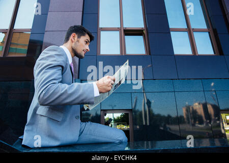 Confident businessman reading newspaper outdoors Stock Photo