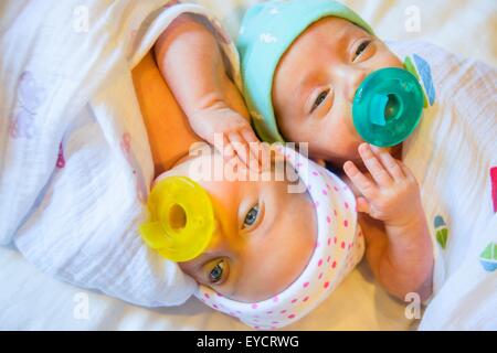 Twin baby sister and brother sucking on comforter Stock Photo