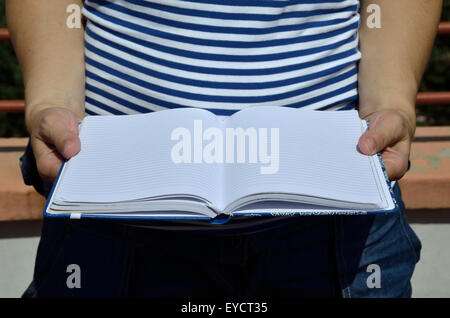 Opened notebook with lines hold in hands Stock Photo