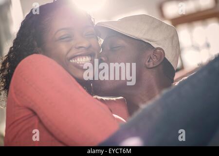 Mid adult man kissing girlfriend on cheek Stock Photo
