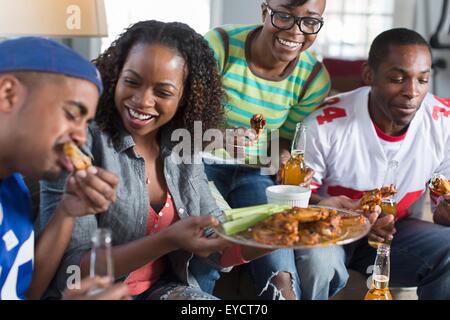 Group of adult friends eating takeaway on living room sofa Stock Photo
