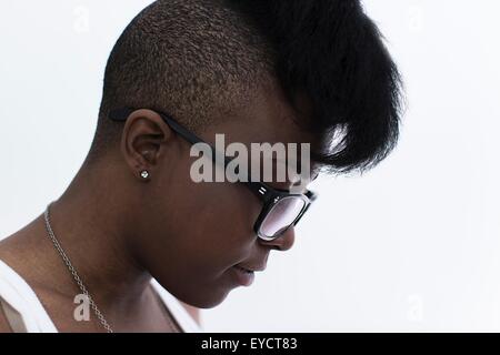 Studio profile portrait of young woman with shaved head and quiff