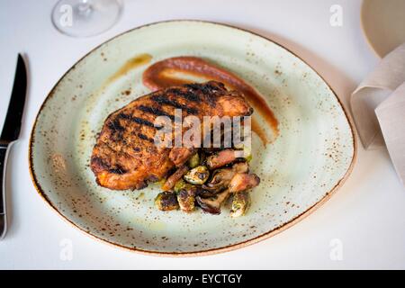 Plate with grilled meat on restaurant table Stock Photo