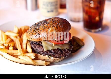 Cheese burger and french fries on restaurant table Stock Photo