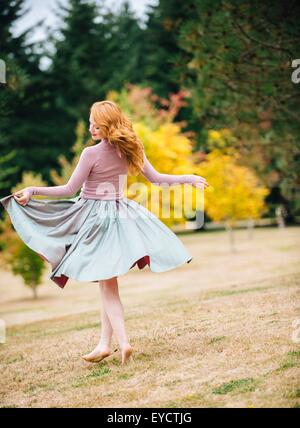 Young female dancer twirling and  lifting skirt in park Stock Photo