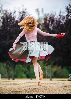 Rear view of young woman dancing and twirling and in park Stock Photo