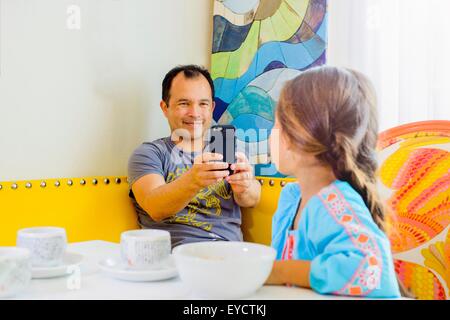 Mature man photographing daughter on smartphone Stock Photo
