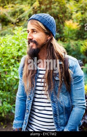 Mid adult man with long hair, wearing hat Stock Photo