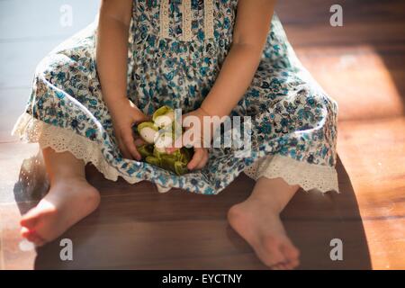 Young girl, sitting on floor, playing with toy, low section Stock Photo