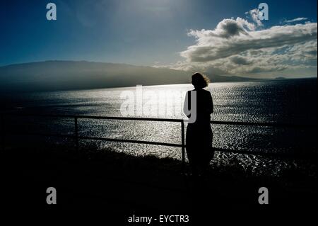 Silhouetted senior woman looking out to sea, Maui, Hawaii Stock Photo