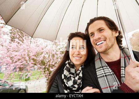 Young couple strolling in park with umbrella Stock Photo