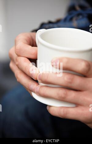 Close up of young mans hands holding coffee mug Stock Photo