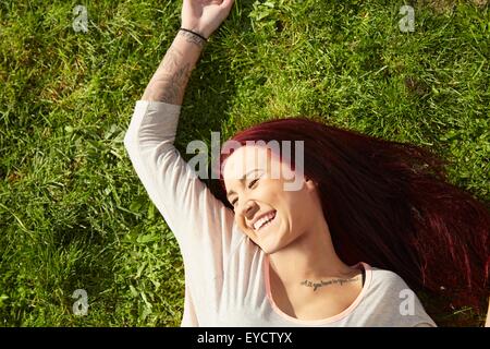 Overhead view of young woman lying on grass laughing