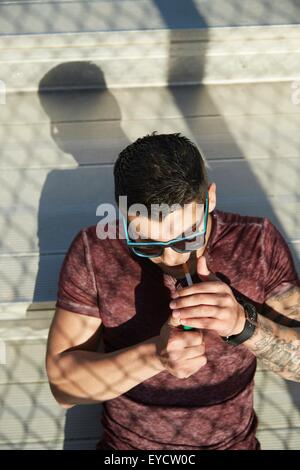 High angle view of young man lighting cigarette on park bench Stock Photo