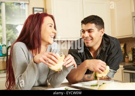 Young couple eating sandwiches at kitchen counter Stock Photo