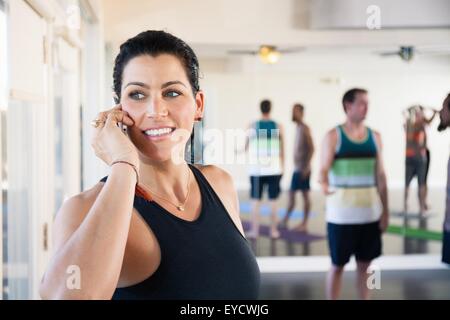 Mid adult woman on cell phone in exercise studio Stock Photo