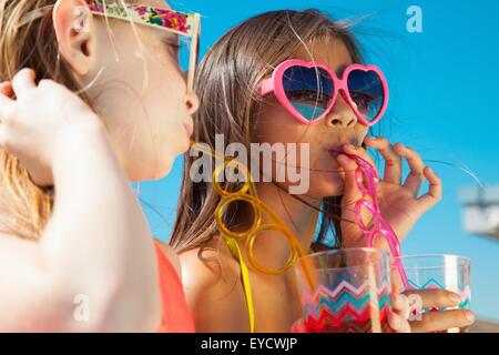 Girls wearing sunglasses drinking through straws Stock Photo