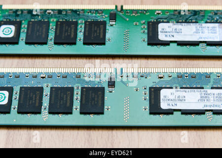 Home computer. Two green DIMM Ram sticks on wooden background. Close up showing black processors and gold coloured connection pins. Stock Photo