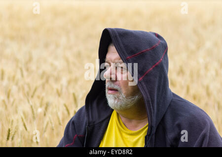 Outdoor portrait of a senior man in cowl against wheat field Stock Photo
