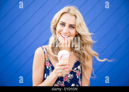 A lovely young woman holds her ice cream cone while posing for the camera. Stock Photo
