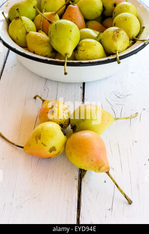 Pile of fresh and ripe pears in a metal bowl on white wooden table Stock Photo