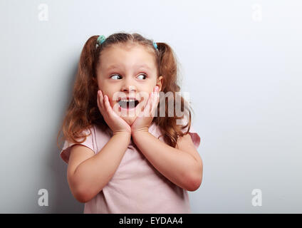 Fun surprising kid girl with open mouth and big eyes looking on empty copy space Stock Photo