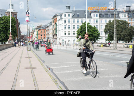 A cyclist checks his phone whilst cycling on the Dronning Louises Bro. Stock Photo