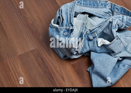 Crumpled jeans left in a heap on the floor. Stock Photo