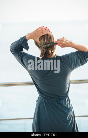 A woman brushes her hair outside having just washed it Stock Photo