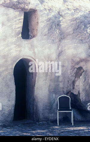 an ancient cave house with a chair in front of the door Stock Photo