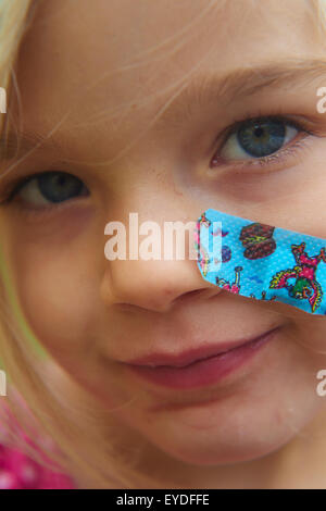 Close up of injured child Girl with plaster on her cheek Stock Photo