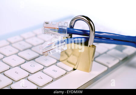 big lock on a computer keyboard, with ethernet cables Stock Photo