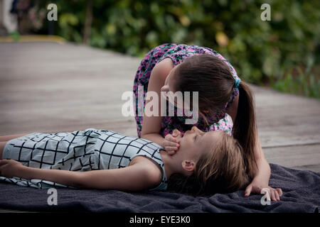 Child practising first aid CPR on another child. Stock Photo