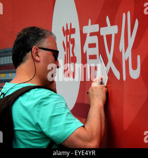 Beijing, China. 22nd June, 2015. Photo taken on June 22, 2015 shows a foreigner filling in poster cards at the Nanluoguxiang alley in Beijing, capital of China. Traditional trading communities in China embody the Chinese culture and become hot spots for city tourism. © Wang Song/Xinhua/Alamy Live News Stock Photo