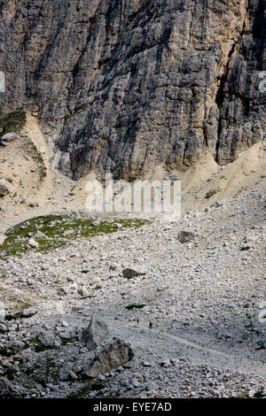 Hikers from Passo Falzarega (Pass) ascend the lower slopes of Lagazuoi  (3,244 m), a Dolomites mountain in south Tyrol, Italy. Lagazuoi is a mountain in the Dolomites of northern Italy, lying at an altitude of 2,835 metres (9,301 ft), about 18 kilometres (11 mi) southwest by road from Cortina d'Ampezzo in the Veneto Region. It is accessible by cable car and contains the Refugio Lagazuoi, a mountain refuge situated beyond the northwest corner of Cima del Lago. The mountain range is well known for its wartime tunnels. Stock Photo