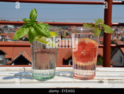 Two glasses of fresh drinks with citrus slices and green fresh leaves - shot outdoor Stock Photo