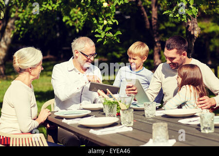 happy family with tablet pc at table in garden Stock Photo