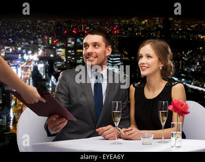 waiter giving menu to happy couple at restaurant Stock Photo