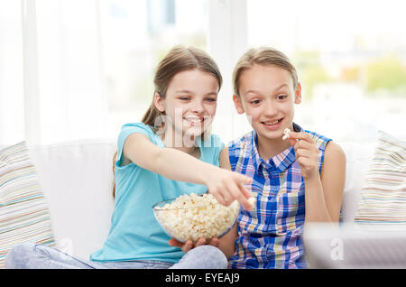 happy girls with popcorn watching tv at home Stock Photo
