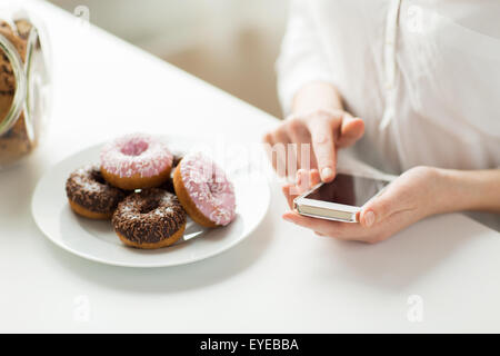 close up of hands with smart phone and donuts Stock Photo