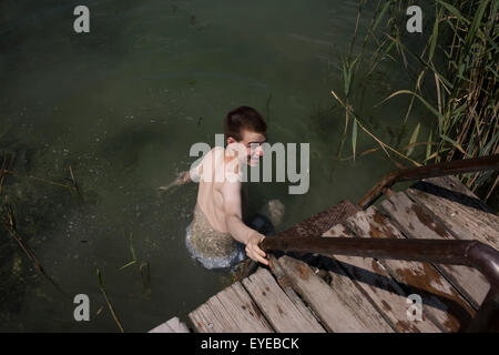 A 17 year-old boy enters a fresh water lake in Kaltern-Caldaro, south Tyrol, northern Italy. Stock Photo