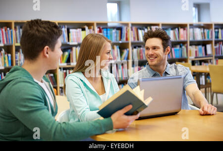 happy students with laptop and books at library Stock Photo