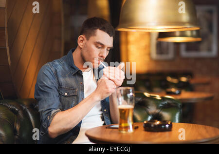 man drinking beer and smoking cigarette at bar Stock Photo