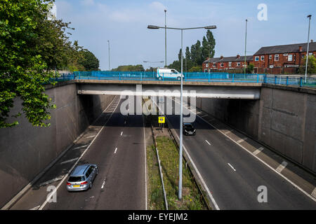 Urban Motorway showing bridge over the motorway with a vehicle traveling in each direction with a small an crossing the bridge Stock Photo