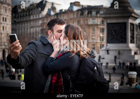 Young couple kissing and taking selfies in Trafalgar Square, London, UK Stock Photo