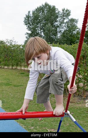 portrait of a young boy climbing monkey bars Stock Photo