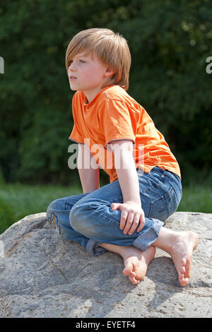 portrait of a young boy sitting on a rock Stock Photo