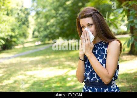 young woman blowing her nose in the park Stock Photo