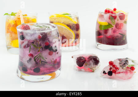 Summer fruit refreshment next to frozen fruit in ice cubes on white background Stock Photo